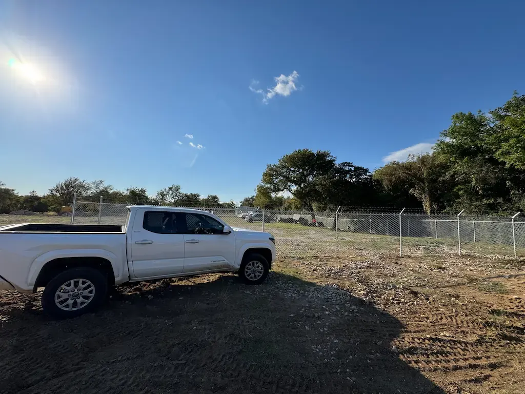 New chain link fence enclosing an open gravel lot with a pickup truck inside