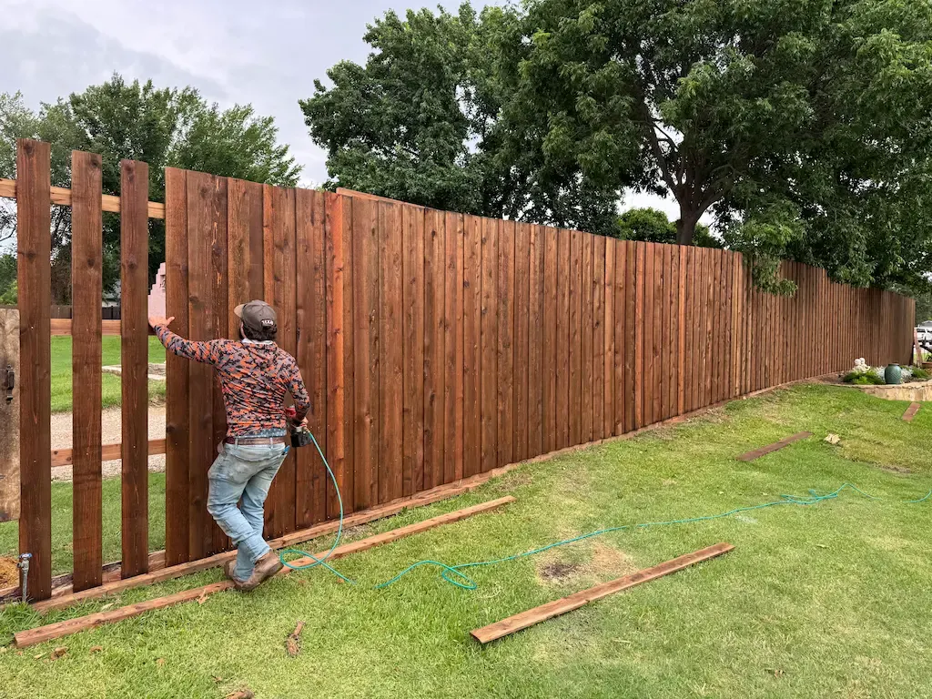 Installer fastening cedar pickets to a new privacy fence